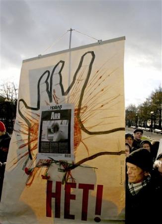Participants hold a poster depicting Anna Politkovskaya