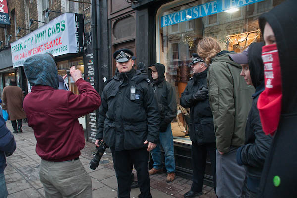Protesters photograph police who question a youth