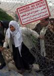 A Palestinian Woman Climbs under a fence - Photo