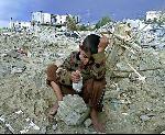 A Palestinian boy sits atop the rubble of his home