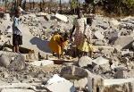 Zimbabwean children scavenge for pieces of wood from the rubble of a destroyed h