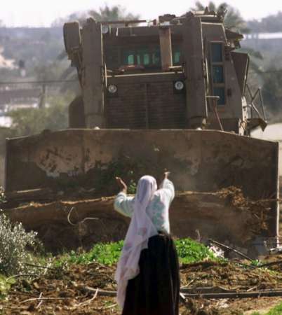 A Palestinian woman confronts an Israeli Caterpillar made D-10 Bulldozer