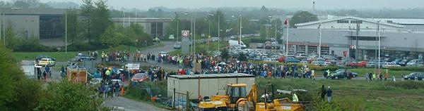 Protestors slowly cross the road in large numbers (wide angle)