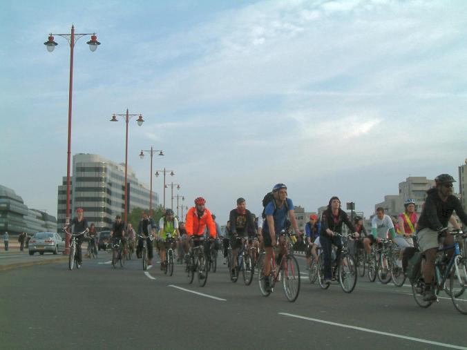 People cycle off the bridge into the City of London