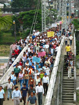 Demonstrators march peacefully across the main footbridge in the town of Tena.