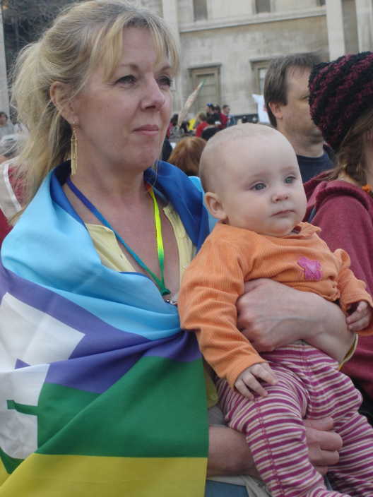 A mother and child draped in a peace flag in Trafalgar Square