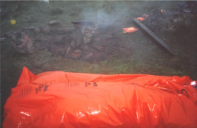 Sleeping in survival bag next to remains of fire.