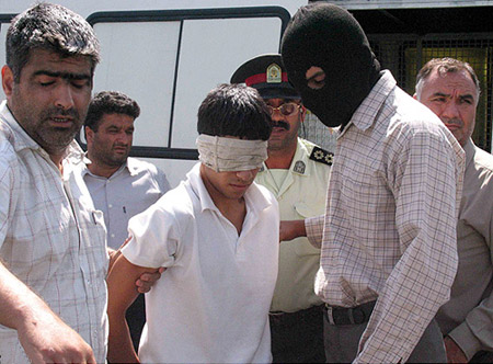 Blindfolded, the boys are led away by a masked executioner