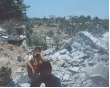 Boys sitting on the rubble of their house in Al-Khader