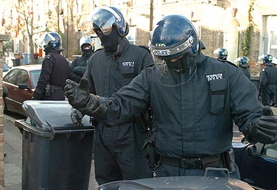 'Move along please!'. (Bored riot cops harrass dustbins.