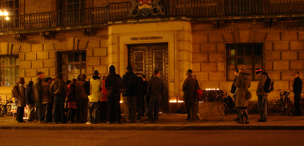 About twenty of us listen to the reading of names of the dead