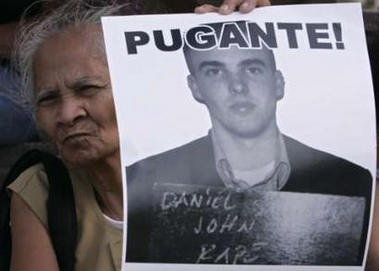 A protester holds a picture of a U.S. marine convicted of rape