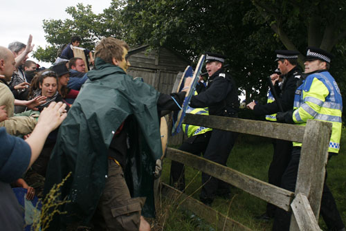 Batton veilding cops trying to keep protesters of the grass.