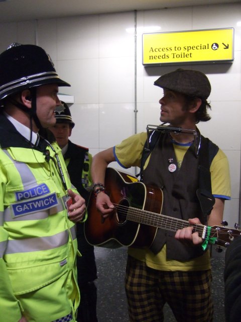 No music! a protester being prevented from playing his guitar at Gatwick Airport