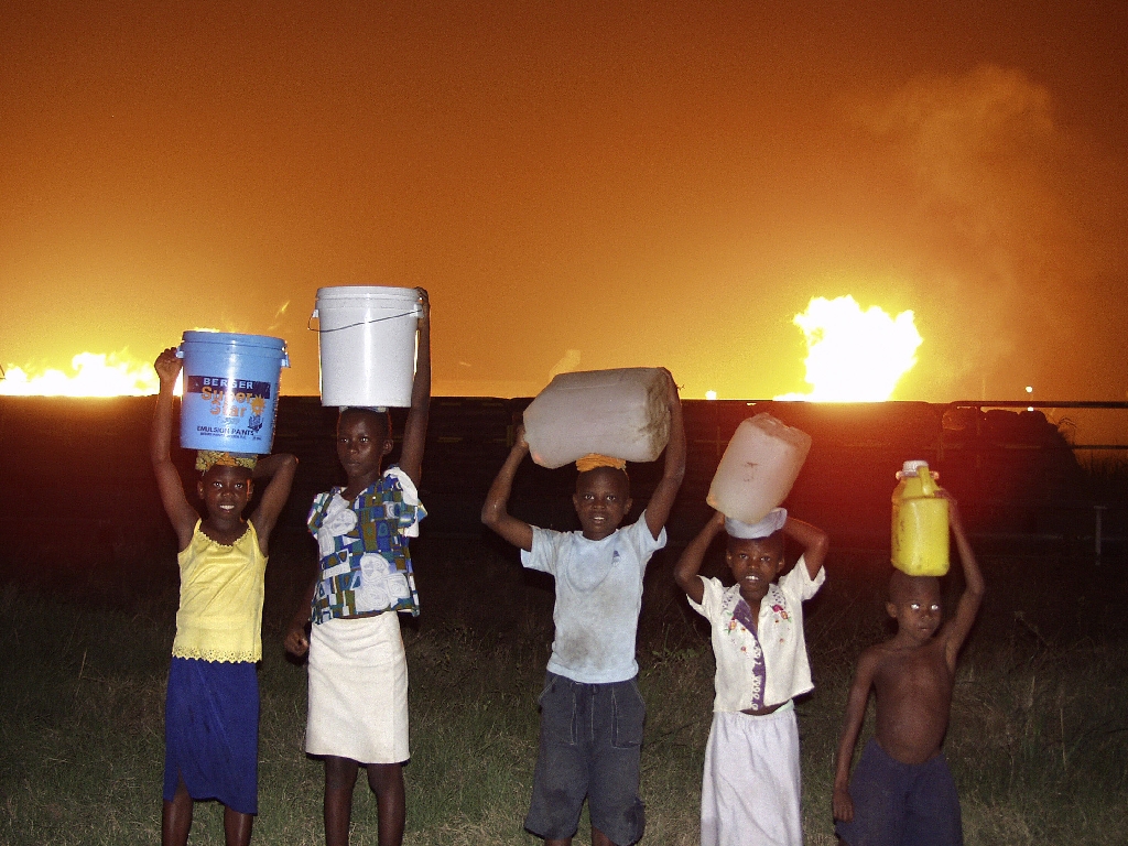 Children collecting water near a Shell gas flare in Nigeria