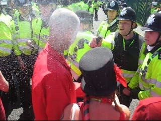 A particularly violent policemen sprays pepper spray into the face of protester