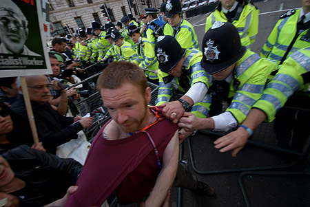 police officers attempt to grab people from the crowd which has formed in front