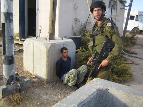 Soldiers guard a checkpoint prisoner