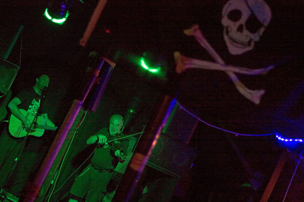 Attila the Stockbroker and David Rovics on stage together, with pirate flag in f