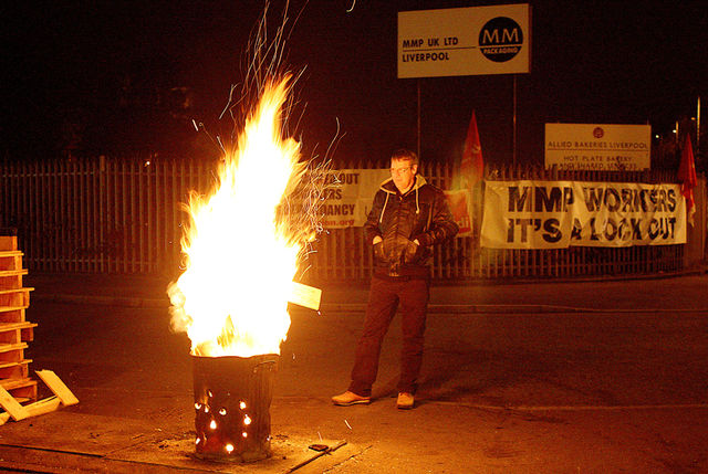 A picketer keeps the fire burning through the night in Bootle this week