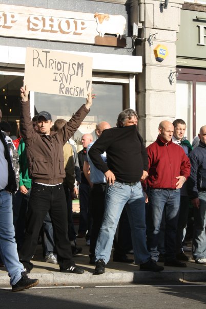 Pretending he isn't racist (brown jacket, holding banner, WDL demo)
