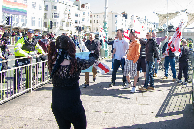Anti-Fascist woman approaches Fascists with small banner