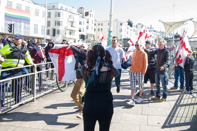 Fascist uses bundle of flag-poles to attack woman